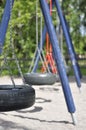 Blue and orange tyre swing set on a children\'s playground on sunny summer day. Tire swing with black tires, metallic chains