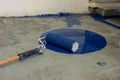 Blue paint roller on concrete floor during renovation project suggesting renovation project. Royalty Free Stock Photo
