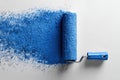 A blue paint roller is on a white surface with blue paint Royalty Free Stock Photo