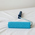 Blue paint roller on a white surface, featuring a textured cylindrical sponge applicator Royalty Free Stock Photo