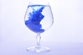 Blue paint in water in a crystal glass on a white background Royalty Free Stock Photo