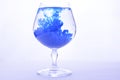 Blue paint in water in a crystal glass on a white background Royalty Free Stock Photo