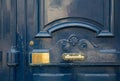Blue painted antique door closeup with curved frame and elegant volute carving wooden panel with shiny brass plate and door handle
