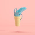 Blue painted banana in ice-cream cone floating on pastel pink background