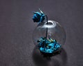 Blue painted leaf in a glass vase and dry rose painting blue on a black paper background with shadows. Royalty Free Stock Photo