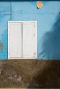 A blue painted wall with a white window. Royalty Free Stock Photo