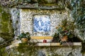 Blue painting of the Virgin Mary in a natural environment with mossy stone walls Royalty Free Stock Photo