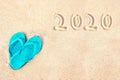 Blue pair of flip flops on the beach, 2020 written in the sand. Tropical new year holiday card Royalty Free Stock Photo