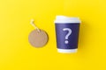 Blue paper coffee cup mockup with question mark and tag label on yellow background Royalty Free Stock Photo