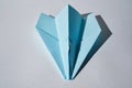 Blue paper plane lying on white background with hard shadows. Royalty Free Stock Photo