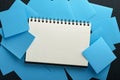 Blue paper stickers and notepad or book in middle on black background. Sticky notes blank with copy space ready for your message. Royalty Free Stock Photo