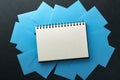 Blue paper stickers and notepad or book in middle on black background. Sticky notes blank with copy space ready for your message. Royalty Free Stock Photo