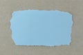 Blue paper tear on brown cardboard background. Royalty Free Stock Photo