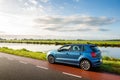 A blue parked car on the side of the road near the ringvaart canal in Abbenes