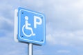 A blue parking sign for the disabled, against a blue sky background Royalty Free Stock Photo