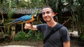 Blue Parrot / Macaw bird on Men`s arm in Macaw Mountain Bird Park, Honduras.