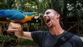 Blue Parrot / Macaw bird on Men`s arm in Macaw Mountain Bird Park, Honduras.