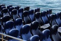 Blue passenger empty seats at a pleasure boat at the pier, a lot of blue seats, no people, against the background of the sea, conc Royalty Free Stock Photo