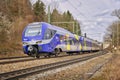 Blue passenger train traveling through a rural landscape