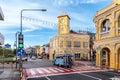 Blue passenger vehicle navigates a busy intersection in Phuket Old Town, with the iconic yellow Sino-Portuguese clock tower in the