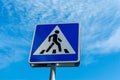 Blue pedestrian crossing sign close up against a cloudy sky Royalty Free Stock Photo