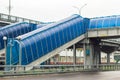 Blue pedestrian tunnel bridge over a highway with multiple exits in the city Royalty Free Stock Photo