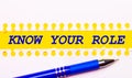 Blue pen and white torn paper stripes on a bright yellow background with the text KNOW YOUR ROLE Royalty Free Stock Photo