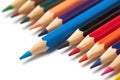 Blue pencil stands out from a raw of other colored pencils lying on an isolated white background