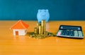 Blue pig bank and coins stack and yellow paper house