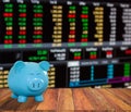 blue pig bank on wood background with blur stock market background,money and saving concept.