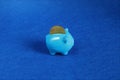 Blue Piggy bank with coin in trendy color of year 2020 on classic blue background. Saving investment, money, banking concept. Copy Royalty Free Stock Photo