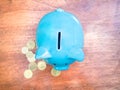 A blue piggy bank and coins on a wooden table Royalty Free Stock Photo