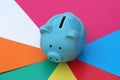 A blue piggy bank is standing against a bright multi-colored background. Royalty Free Stock Photo