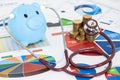 Blue piggy bank and stethoscope checking stack of money coins