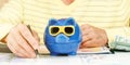 Blue piggy bank in sunglasses against man with pen in hand Royalty Free Stock Photo