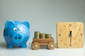 Blue piggy bank with wood clock and stock of coin Royalty Free Stock Photo