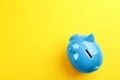 Blue piggy bank on yellow background, top view. Space for text Royalty Free Stock Photo