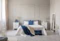 Blue pillow and blanket on white bed in spacious bedroom interior, copy space on empty grey wall Royalty Free Stock Photo