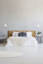 Blue pillow on white bed with wooden headboard in hotel bedroom