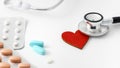 Blue pills with blister packs and stethoscope head on red heart on white background Royalty Free Stock Photo