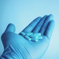 Blue pills in doctors hand on blue background. Life save service