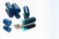 Blue pills in the foreground with one of them open with the medicine out Royalty Free Stock Photo