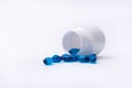 Blue pills spill out from bottle isolated on white background. Royalty Free Stock Photo