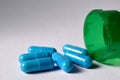 Healthcare pharmacy concept. Blue pills spilling from a green perscription bottle