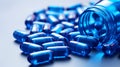 Blue pills spilling out of pill bottle on blue background. Focus on foreground, soft bokeh Royalty Free Stock Photo