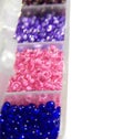 Blue, pink, lilac beads in boxes, closeup