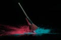 Blue and pink makeup powder brush fall on shiny black surface in a dust cloud Royalty Free Stock Photo