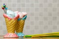 Blue and pink meringue in the pink and blue cones with cupcakes, green and yellow sticks on wood table white background