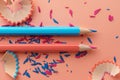 Blue and pink pencils and colored pencils shavings on pink background Royalty Free Stock Photo