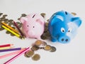 Blue and Pink Piggy bank, bright colored pencils with coins pile, Saving money for future plan and retirement fund concept